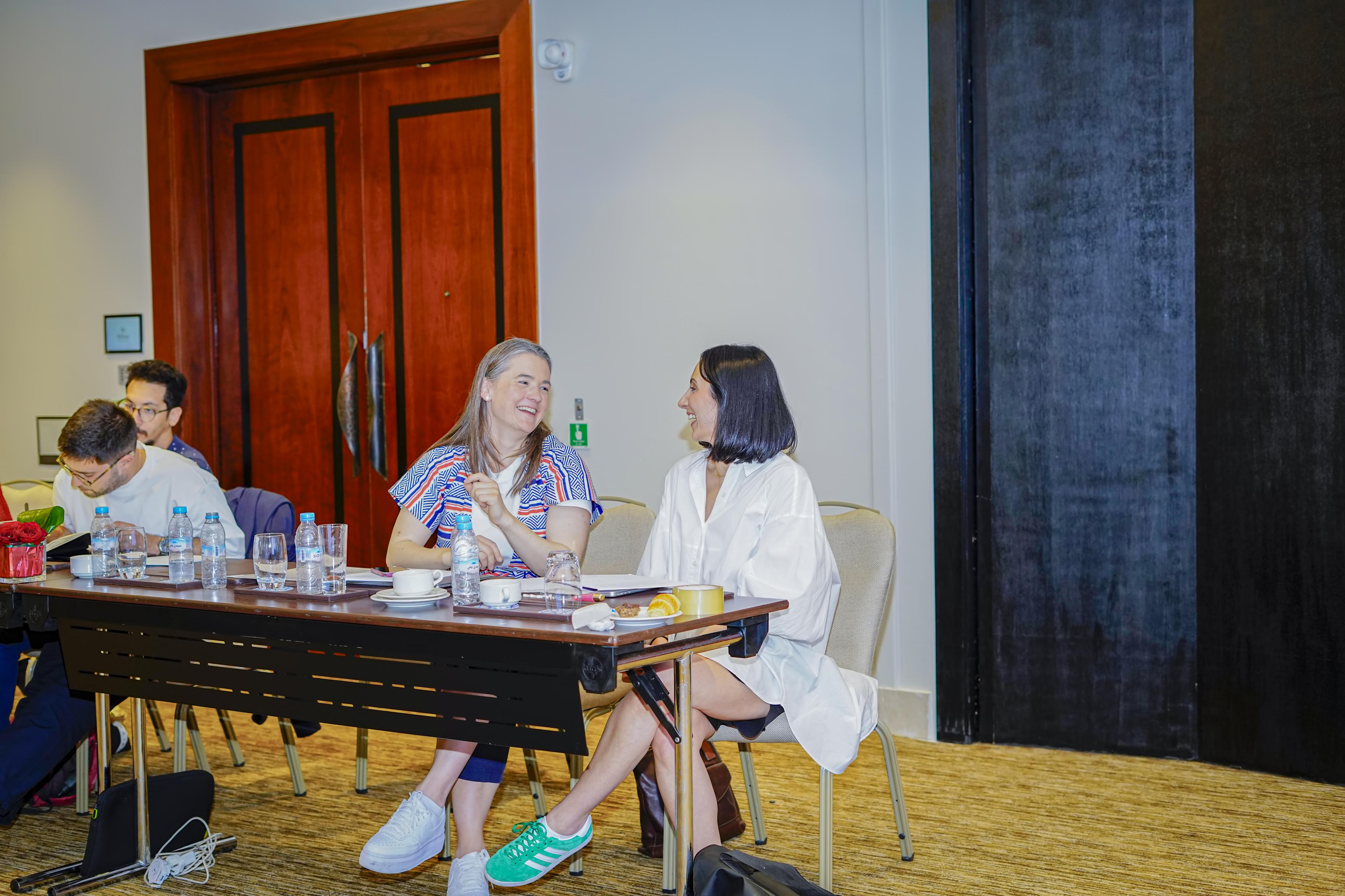 Two people talking and smiling during an indoor conference session.